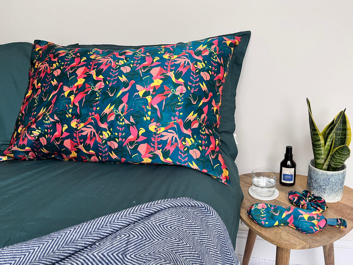 Hummingbird silk pillowcase with zip fasten neatly laying on a complementary green bed set