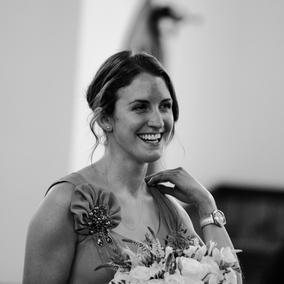 Black and white photo of a maid of honour standing with a bouquet in the church