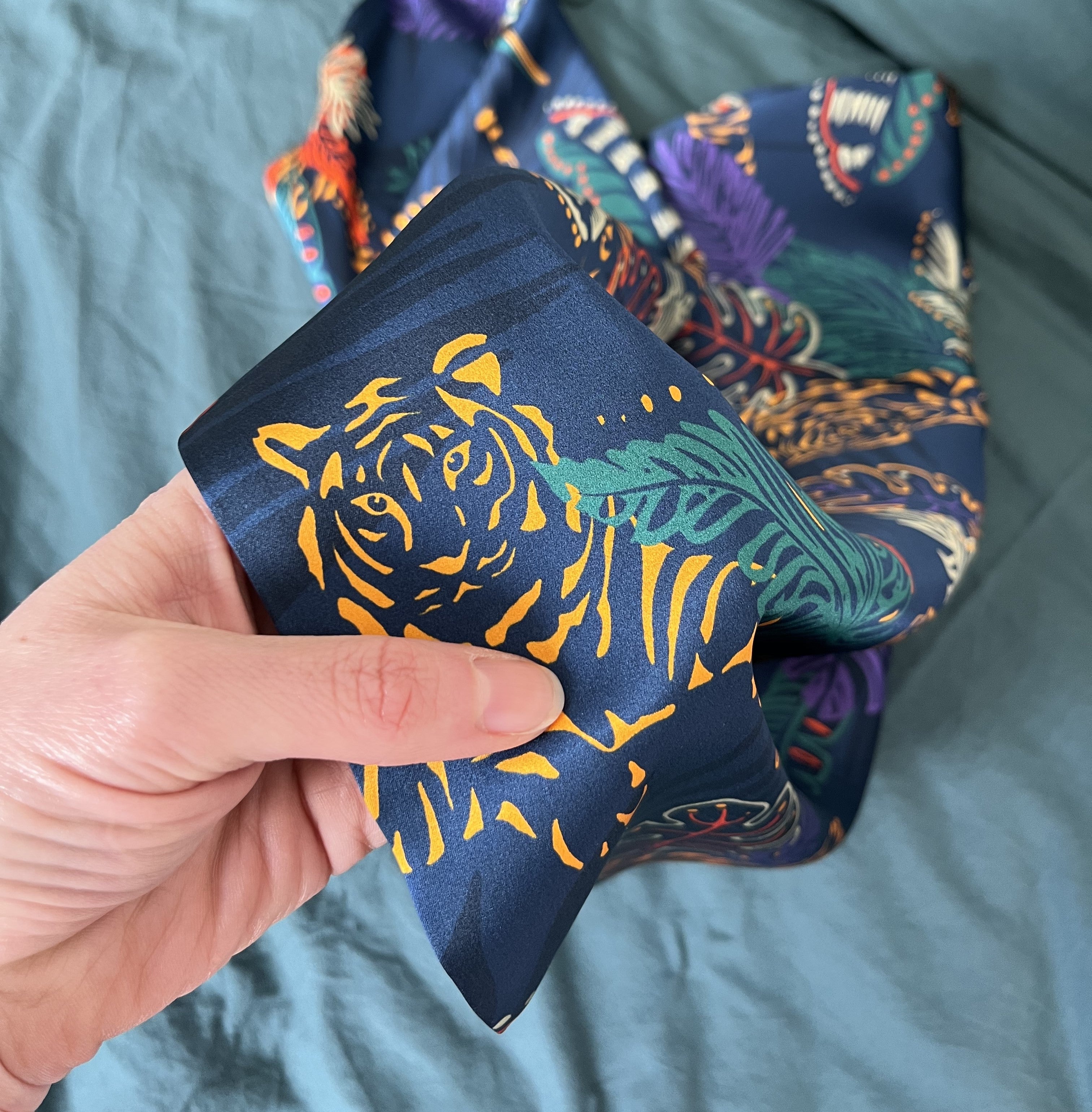 Image of Tropical Tiger MYRN Silk pillowcase on a bed with a thumb