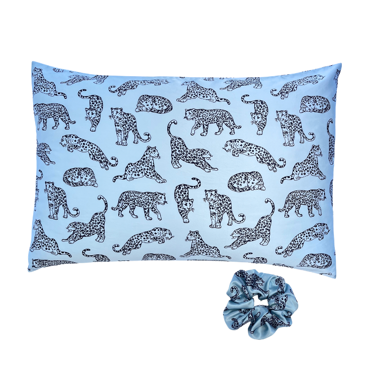 Light blue leopard printed silk pillowcase and matching scrunchie on a white background