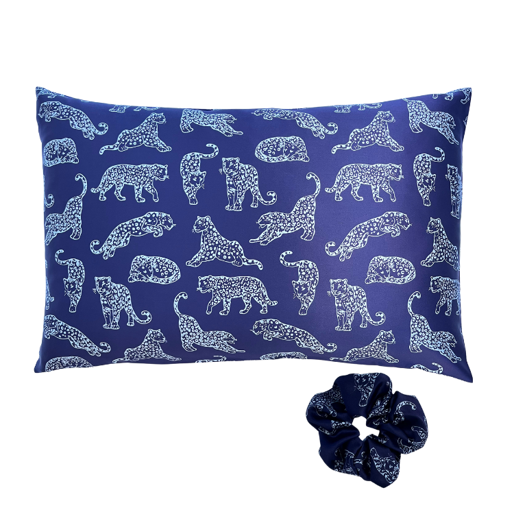 Dark blue leopard printed silk pillowcase and matching scrunchie on a white background