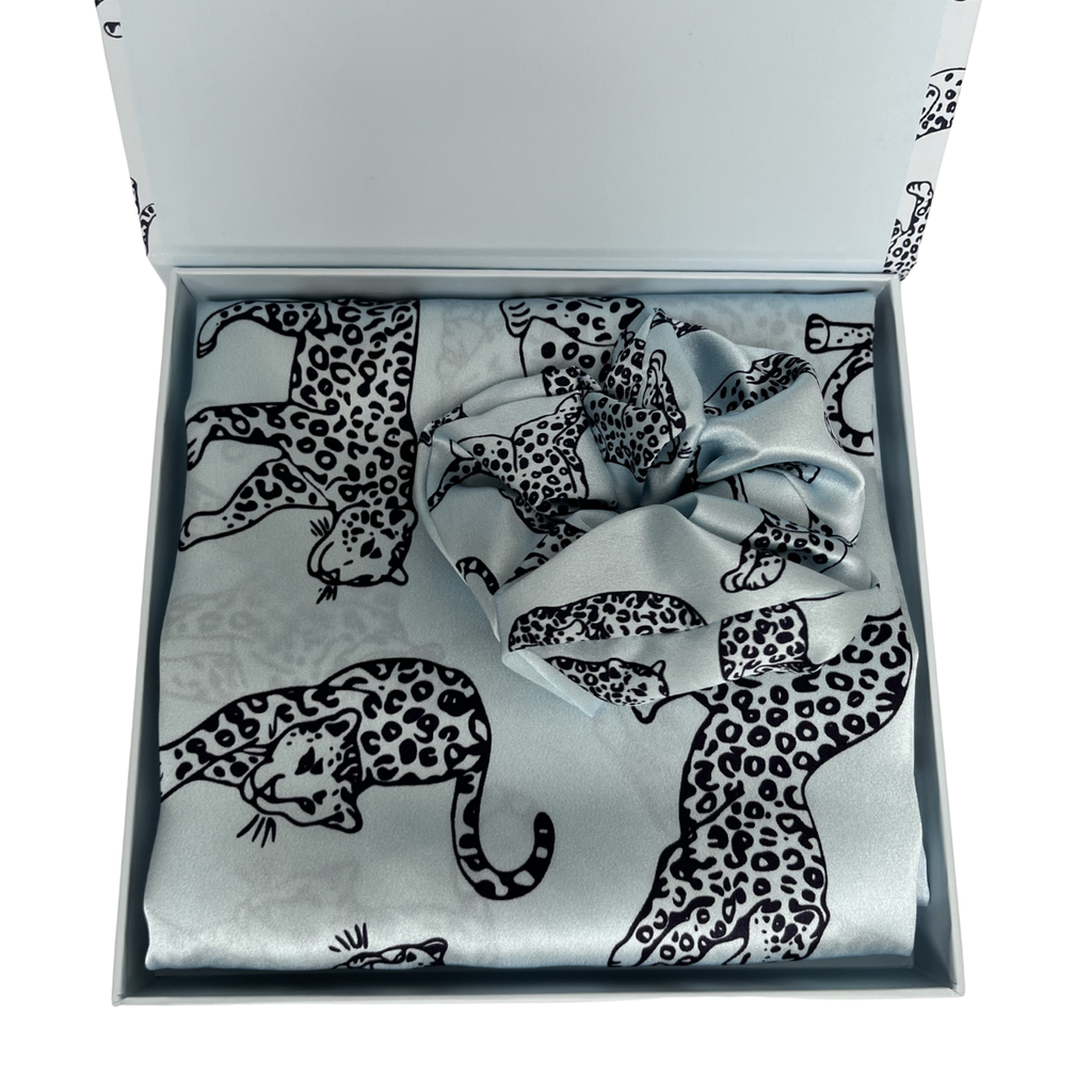 MYRN Silk light blue leopard print silk pillowcase folded with a matching silk scrunchie, inside a presentation box on a white background.
