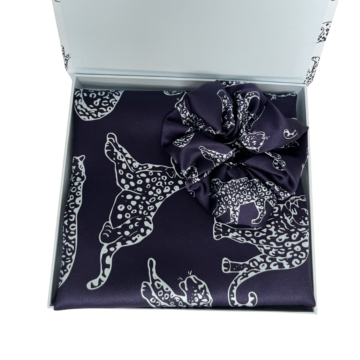 MYRN Silk navy blue leopard print silk pillowcase folded, with a matching scrunchie, inside a presentation box on a white background.