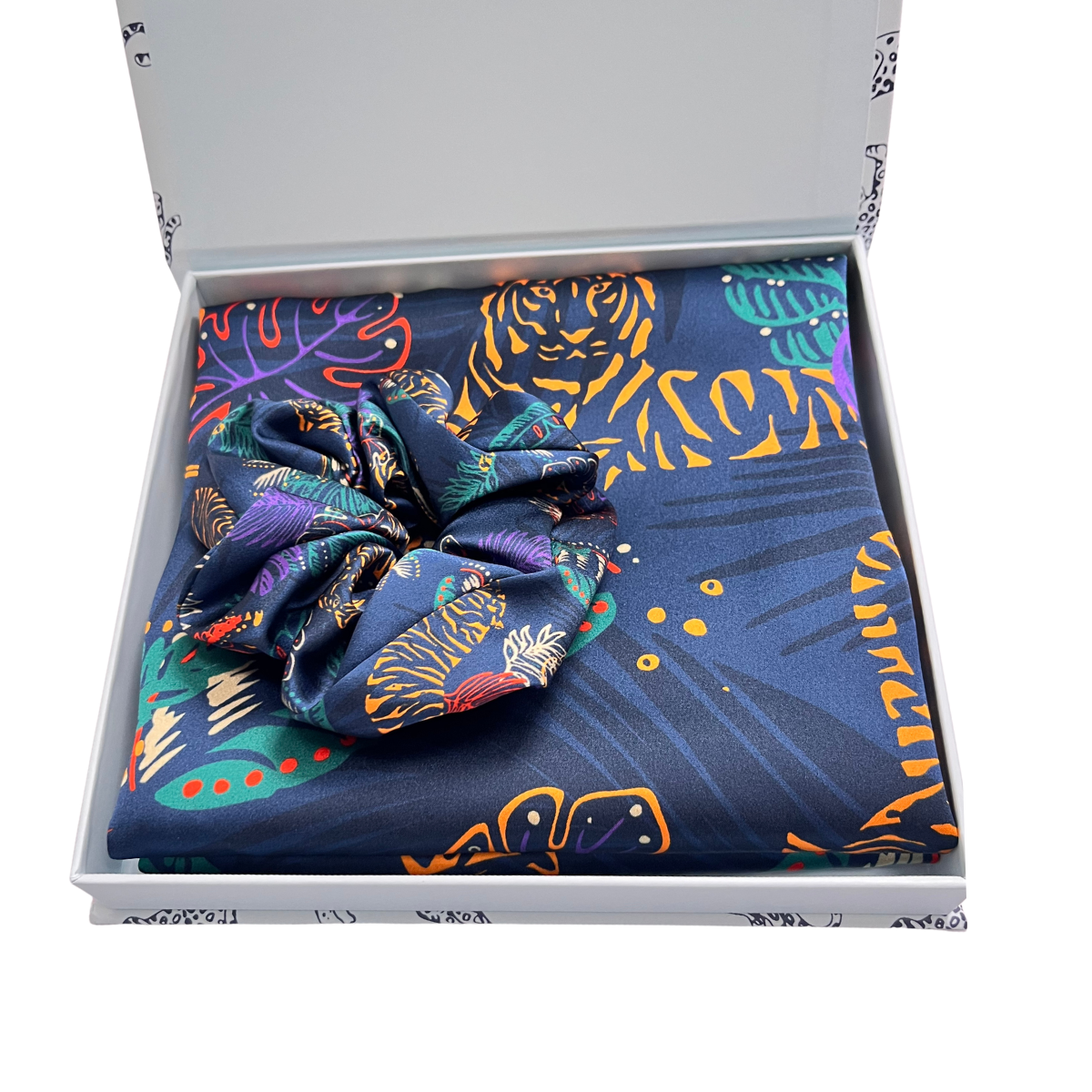 MYRN Silk tiger print silk pillowcase folded, with a matching silk scrunchie, inside a presentation box on a white background.